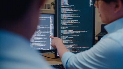 Closeup group of Asian people software developers using computer to write code sitting at desk with multiple screens in office at night. Programmer development concept. Closeup group of Asian people software developers using computer to write code sitting at desk with multiple screens in office at night. Programmer development concept.
