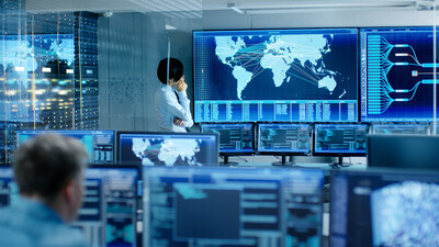 In the System Control Room Chief Engineer Thinks While Standing Before Big Screen with Interactive Map on it. Data Center is Full of Monitors Showing Graphics. In the System Control Room Chief Engineer Thinks While Standing Before Big Screen with Interactive Map on it. Data Center is Full of Monitors Showing Graphics.